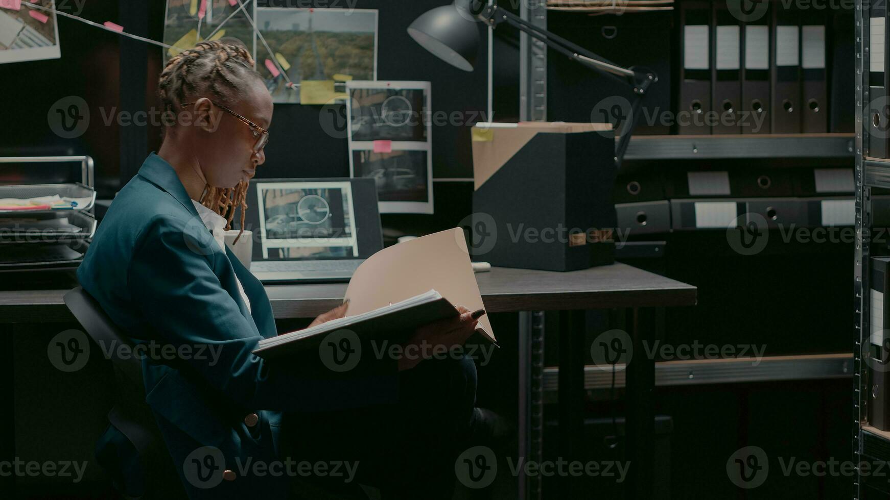 privaat detective lezing misdrijf informatie records in Politie archief kamer, controle toezicht foto's Aan laptop. veiligheid middel aan het studeren geval het dossier in kantoor, dirigeren onderzoek. foto