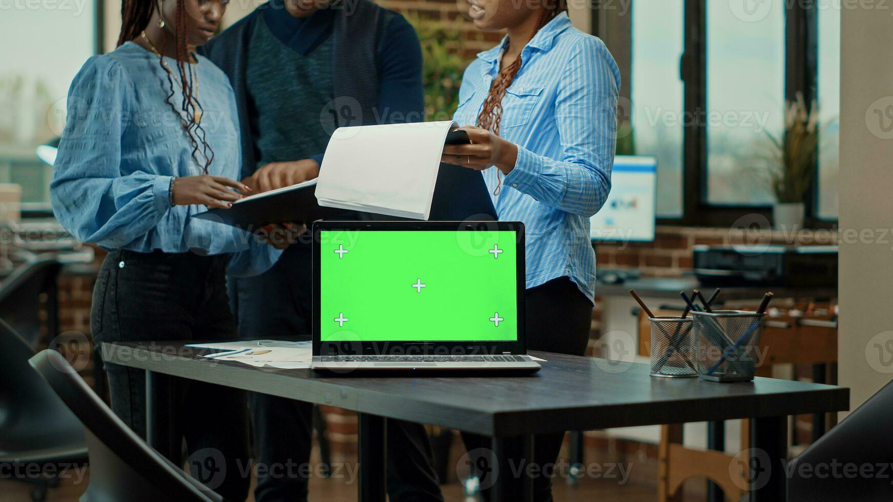 medewerkers team analyseren papieren gebruik makend van groenscherm Aan laptop, mensen werken met geïsoleerd Scherm in coworking ruimte. collega's planning nieuw strategie met blanco chroma sleutel mockup scherm. foto