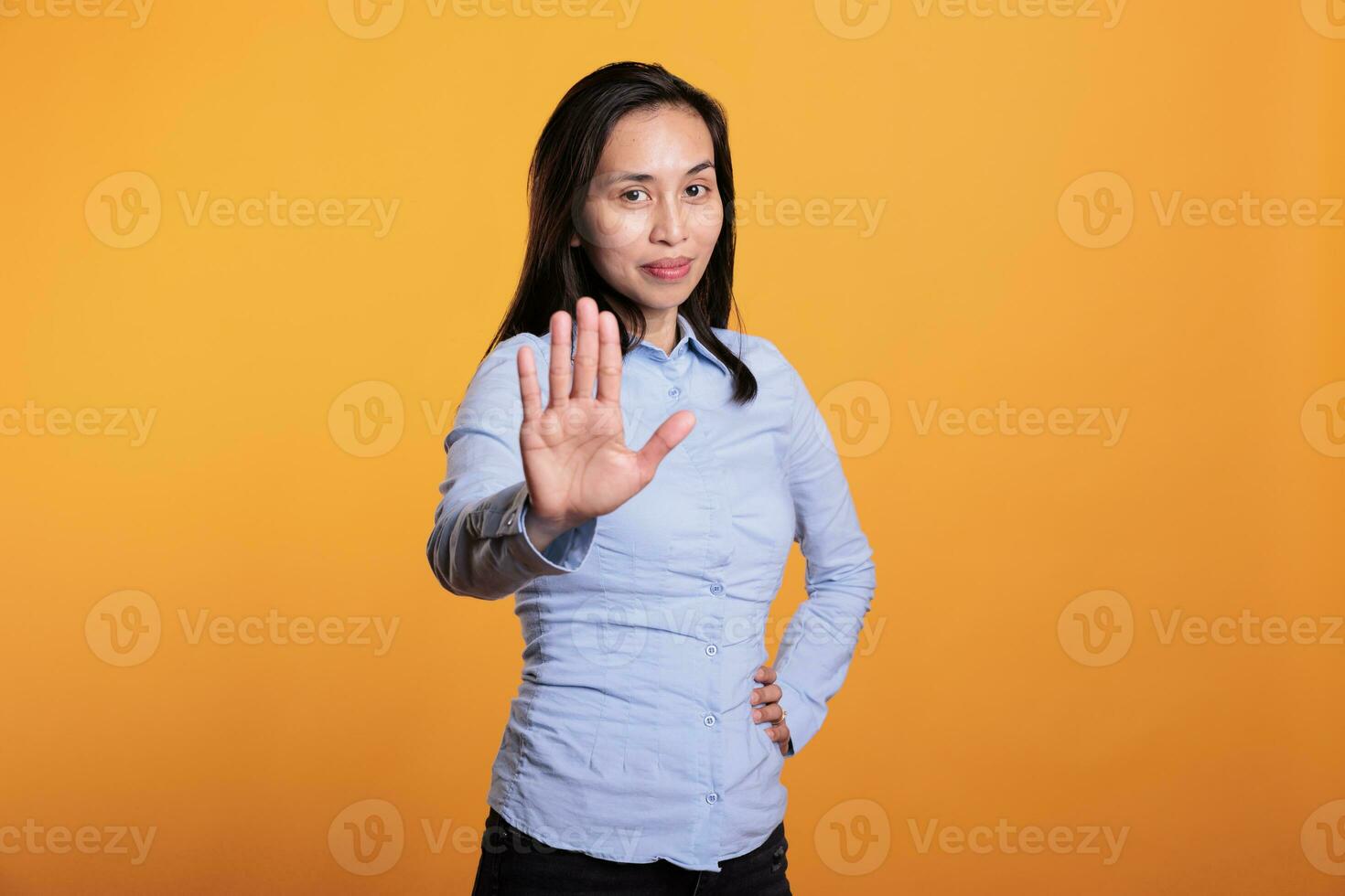 negatief Aziatisch vrouw aan het doen weigering gebaar met hand- in voorkant van camera, poseren in studio over- geel achtergrond. echt jong volwassen tonen hou op gebaar, wezen in ontkenning en uitdrukken afwijzing. foto