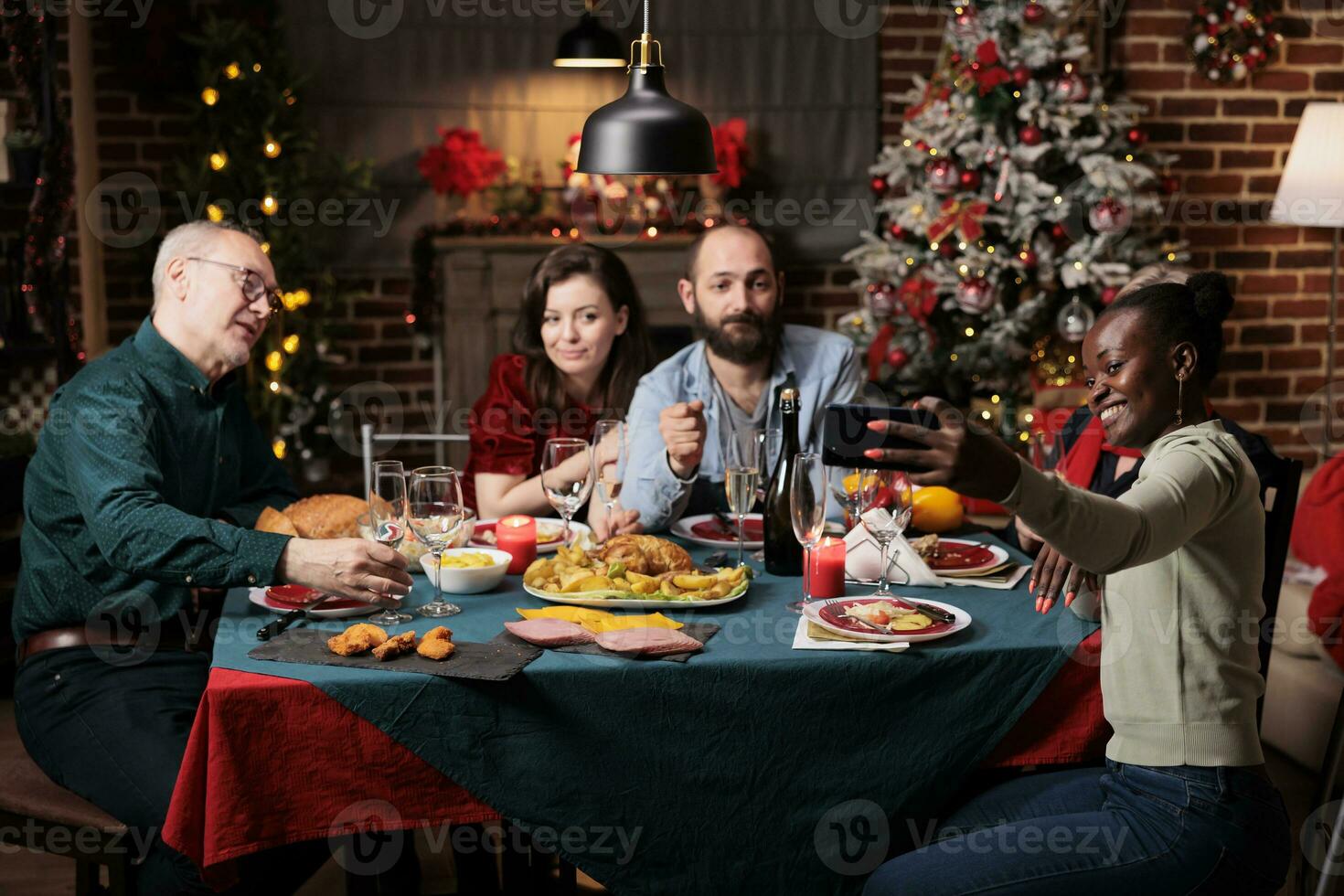 vrienden nemen afbeeldingen Aan Kerstmis vooravond, creëren mooi herinneringen van feest Bij huis. verschillend mensen hebben pret met wijn en voedsel, genieten van foto's voor herinneringen Bij tafel. foto