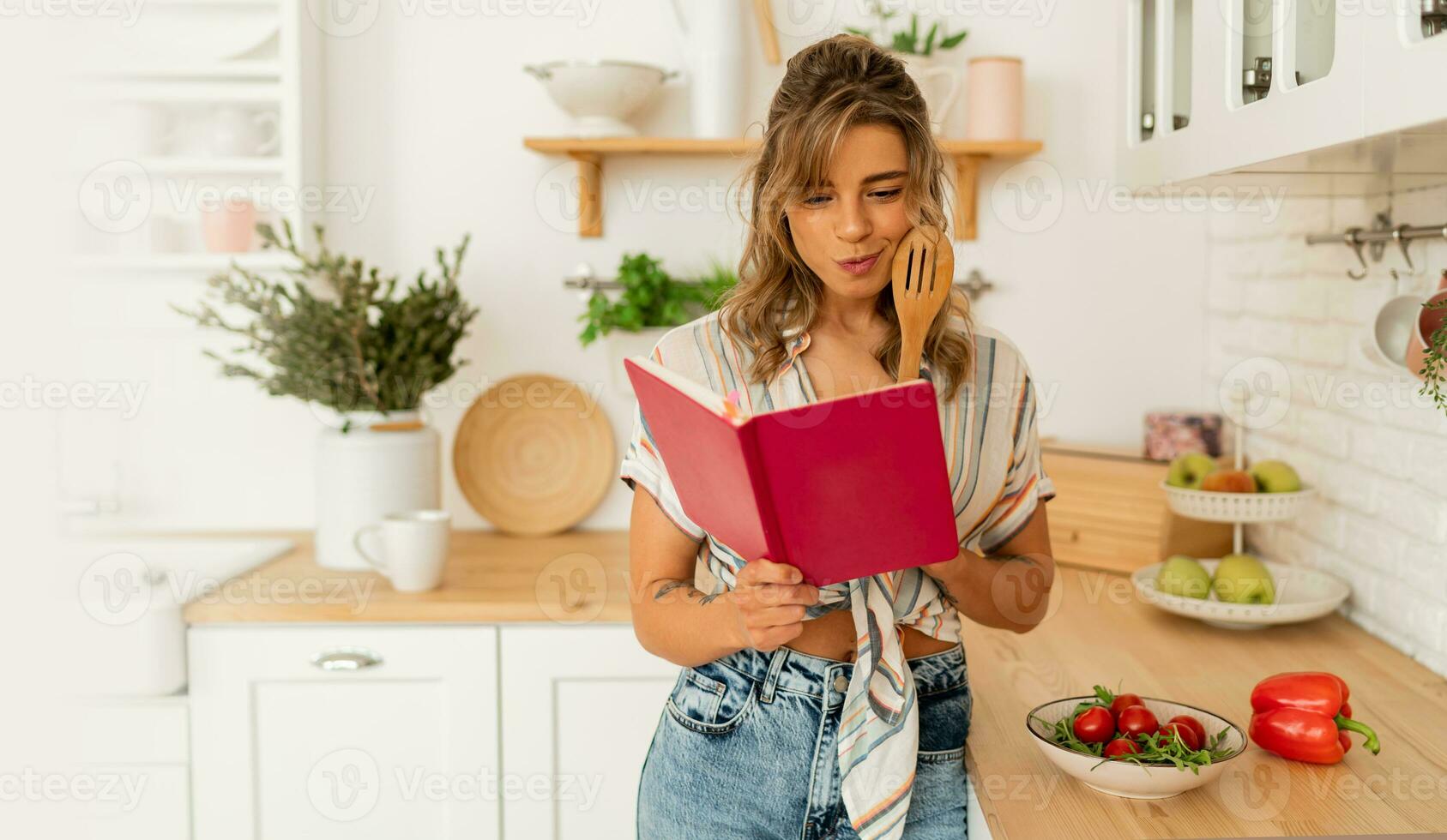 grappig huisvrouw vrouw op zoek Bij recept in kookkunst boek voorbereidingen treffen groente salade Koken voedsel in licht keuken Bij huis. dieet gezond levensstijl concept. foto