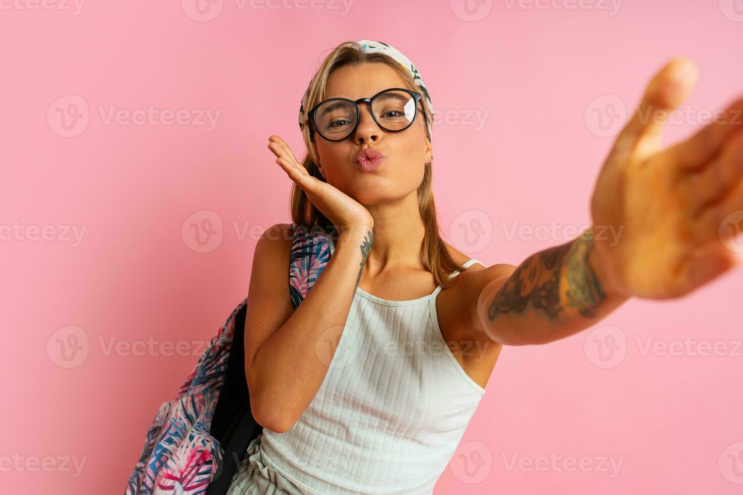 glimlachen leerling vrouw in bril maken zelf portret en poseren Aan roze achtergrond. vervelend elegant zomer kleding en terug pak. foto