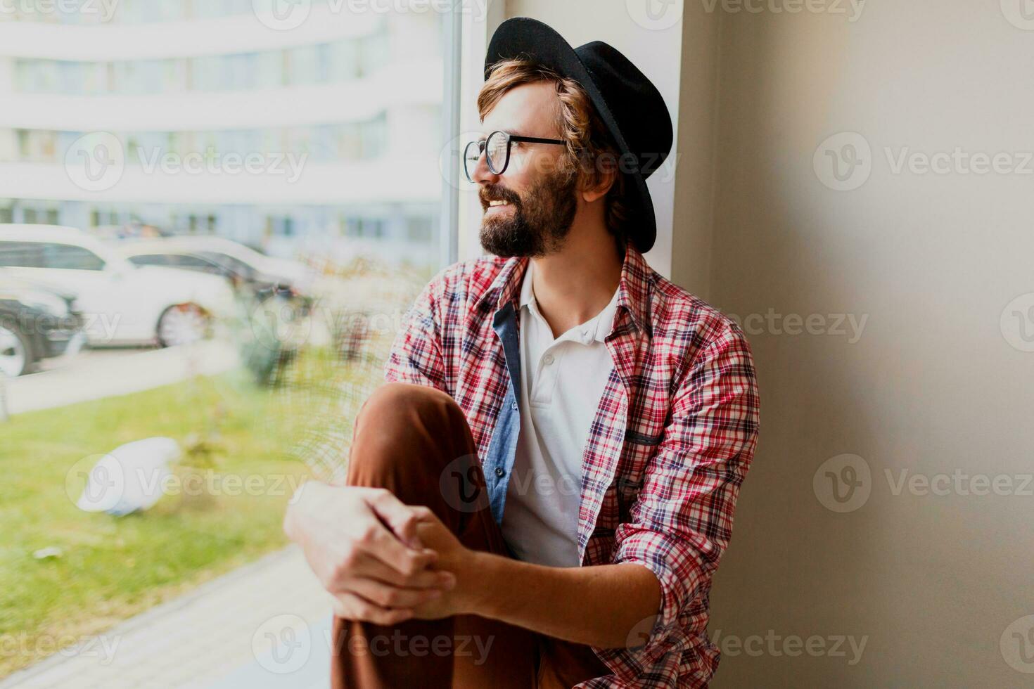 nadenkend Mens met baard in elegant bril en voorjaar kleding ontspannende gedurende werk dag in het bedrijf. hipster kleding. foto