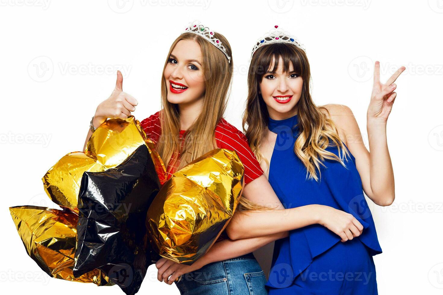 twee gelukkig lief jong Dames met goud ster vormig ballonnen in maskerade kroon hebben pret , poseren Aan wit achtergrond. vieren verjaardag, nieuw jaar . foto