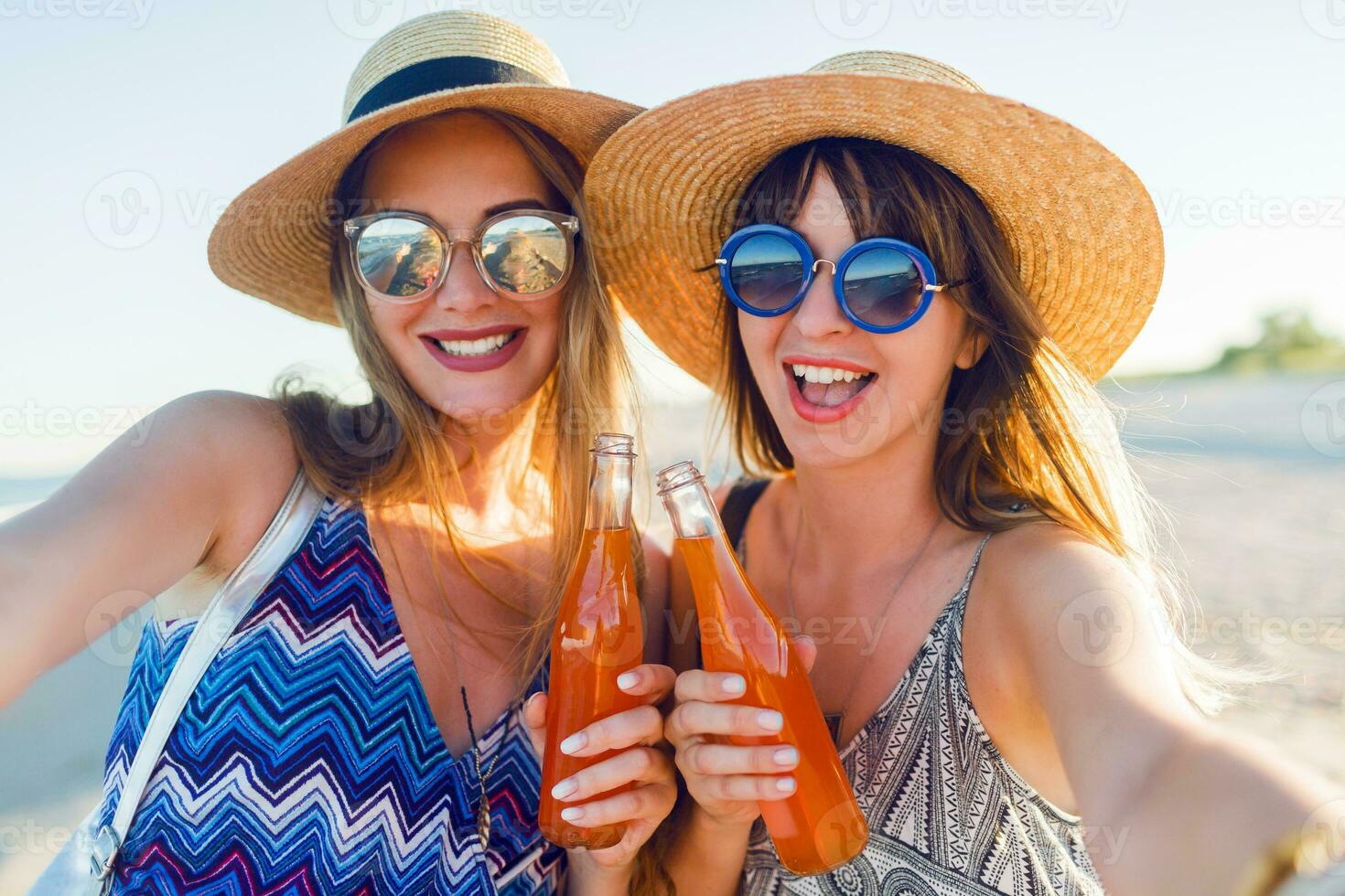 zomer vakantie en vakantie concept. vrienden drinken limonade of alcohol , Holding drank in flessen. genieten van zonsondergang Aan de strand. partij tijd. focus Aan fles. foto