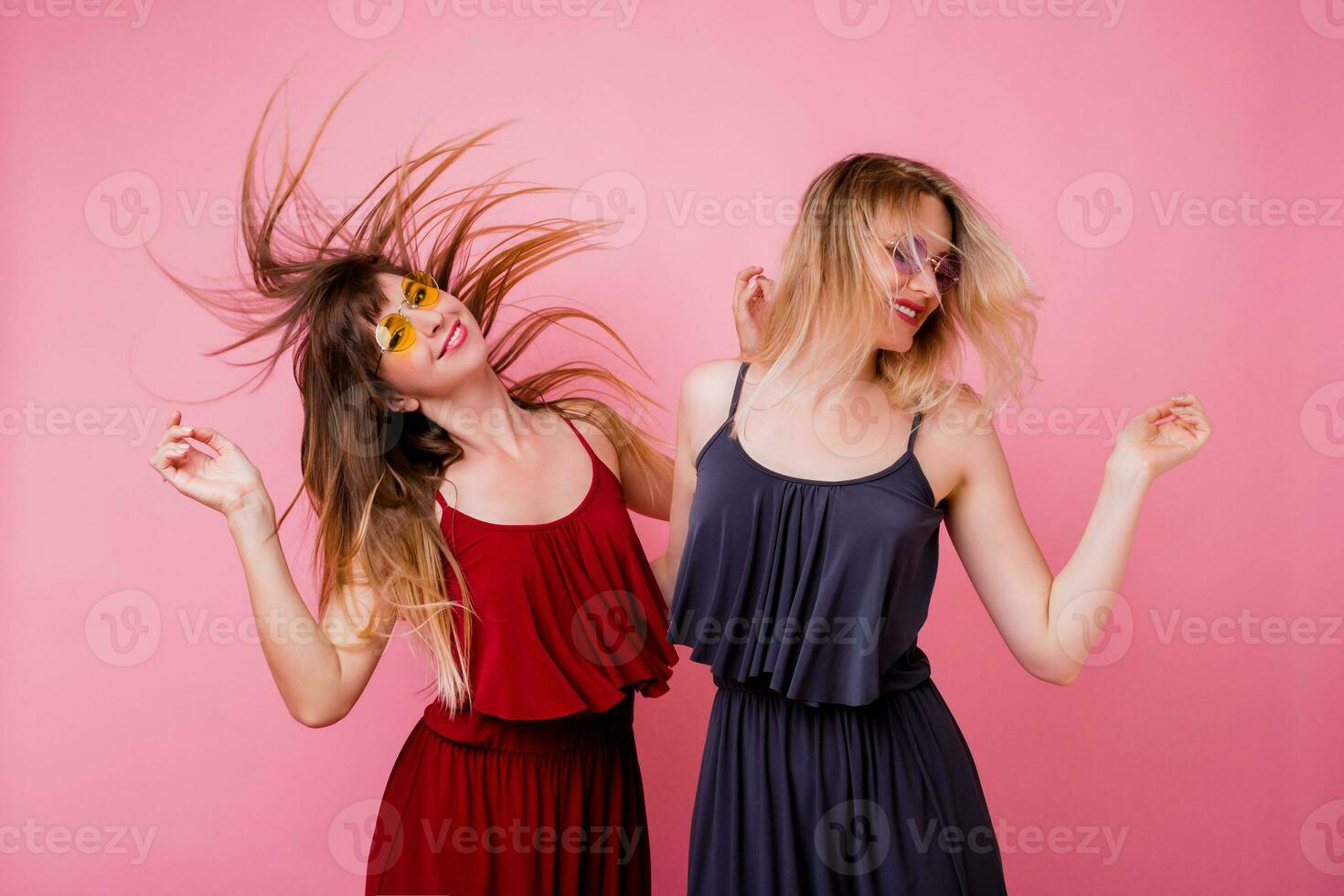 twee zorgeloos vrouw hebben pret en dansen Aan roze achtergrond. flash portret. partij humeur . vergelijkbaar jurk. vriendschap concept. foto