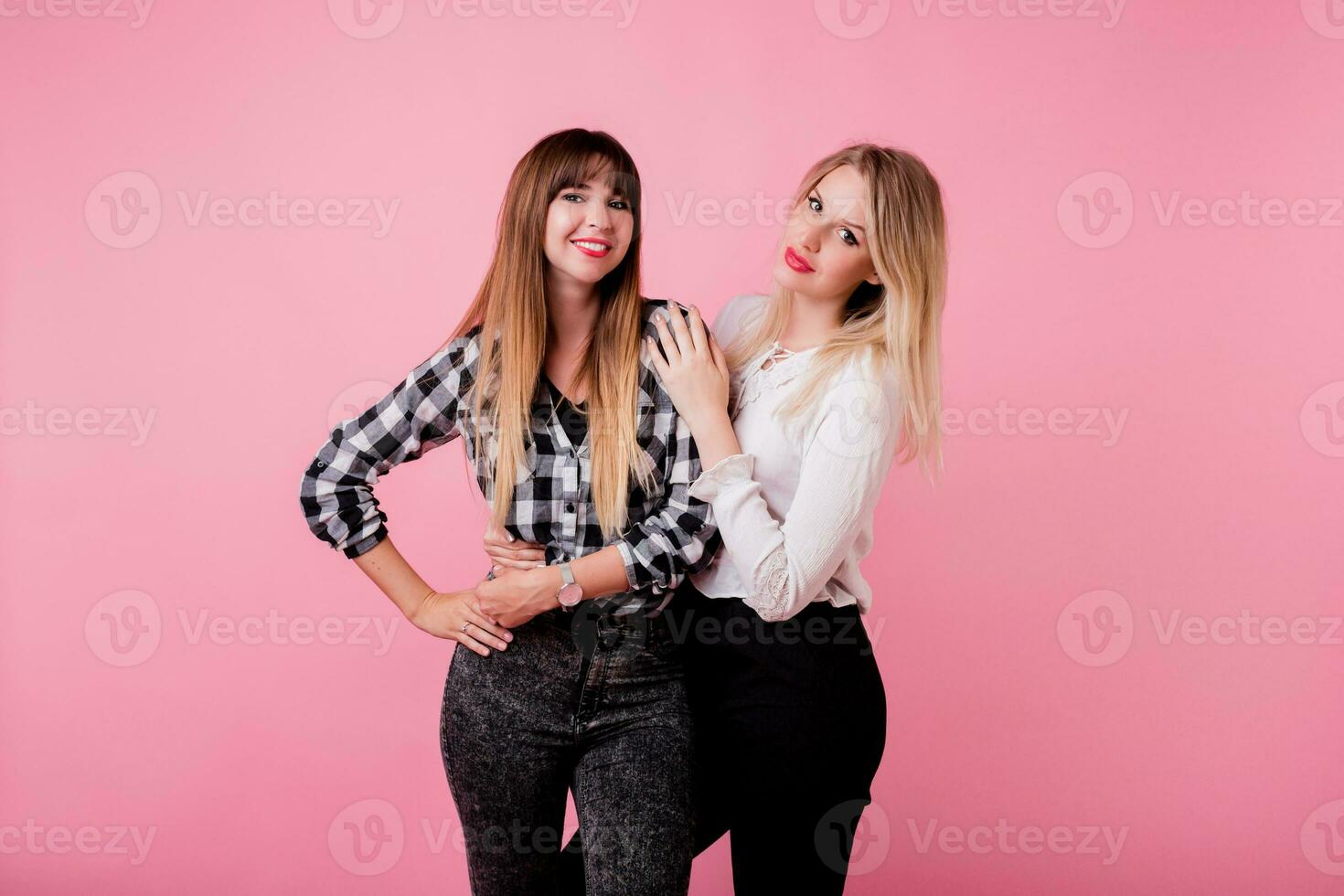 twee glimlachen Dames knuffelen en staand isoleren over- roze achtergrond . brunette en blond meisjes. natuurlijk maken omhoog. foto