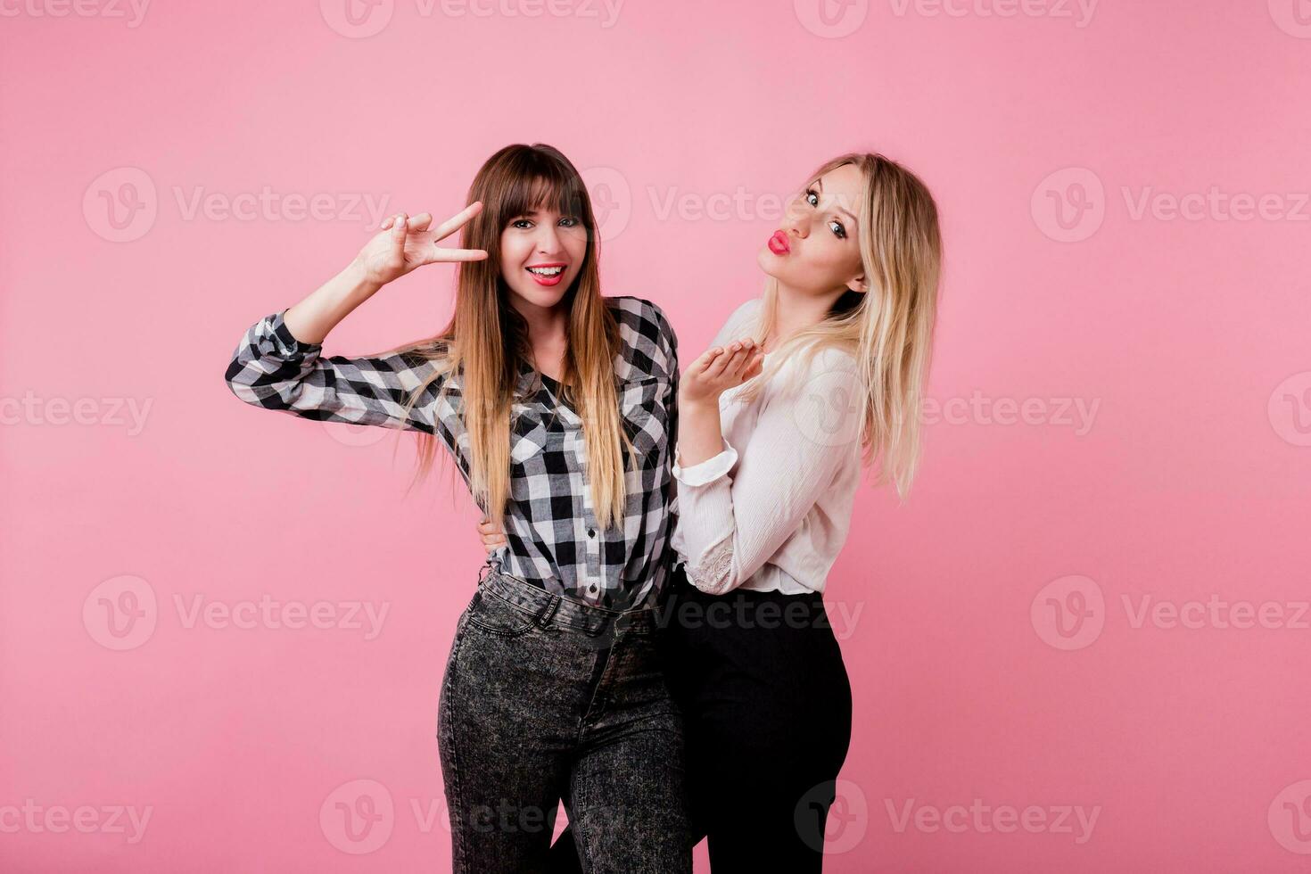 twee glimlachen Dames knuffelen en staand isoleren over- roze achtergrond . brunette en blond meisjes. natuurlijk maken omhoog. foto