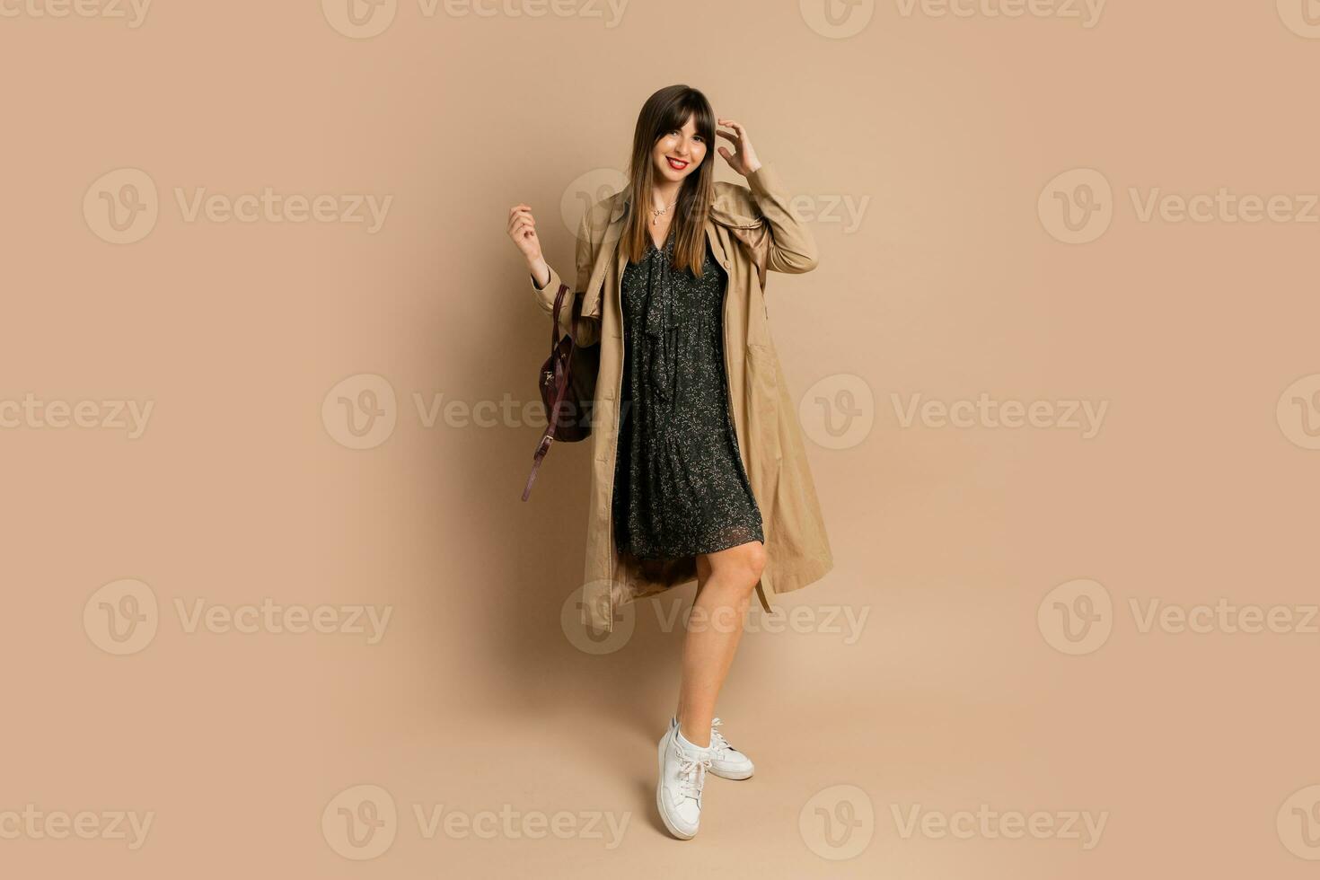elegant brunette vrouw vervelend modieus jas , poseren over- beige achtergrond. winter mode trends. foto
