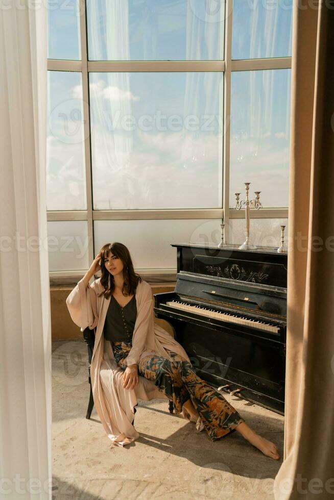 elegant vrouw poseren in de buurt piano in elegant licht studio. foto