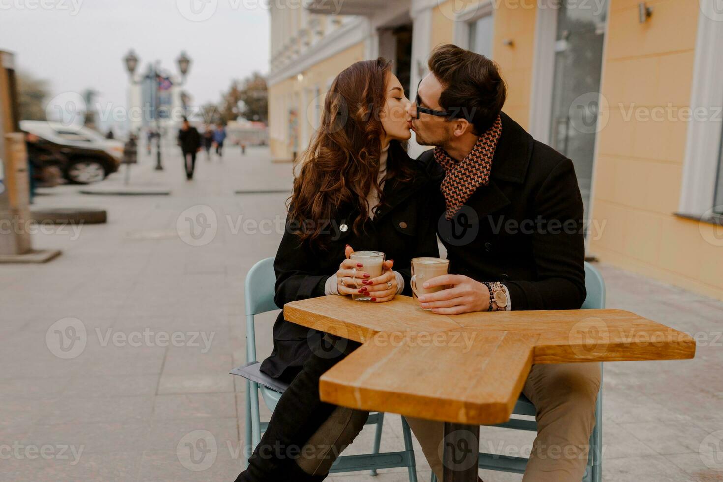 modieus paar in liefde zittend in straat cafe en drinken heet koffie terwijl op reis in Europa. foto