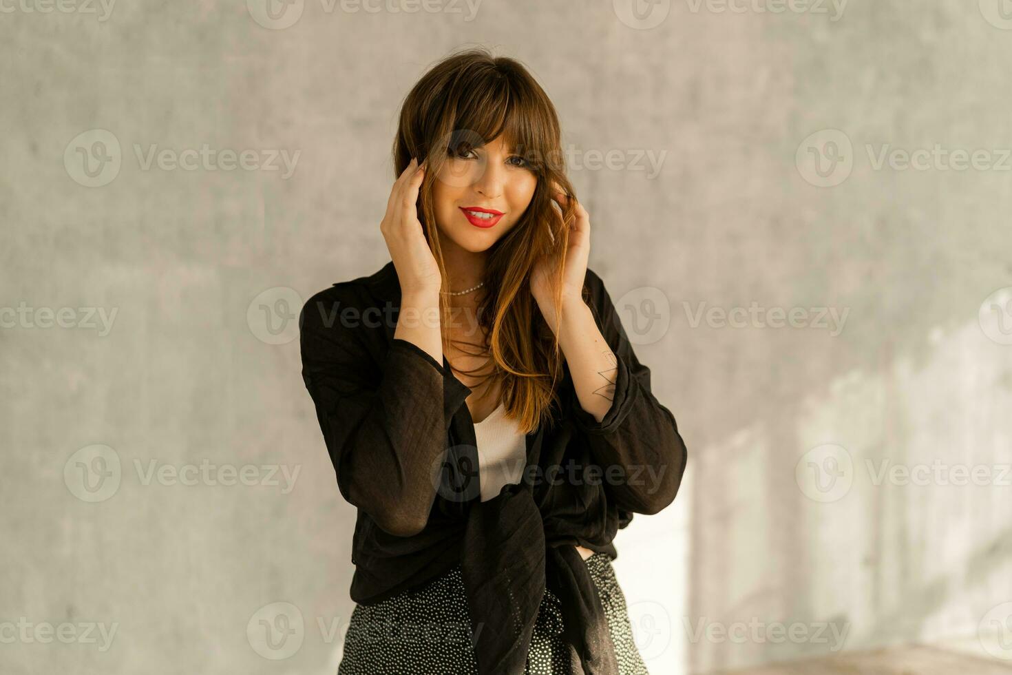 mode foto van brunette vrouw met rood lippen in gewoontjes elegant herfst uitrusting. poseren over- grijs stedelijk muur.