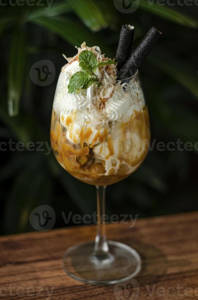 gastronomische biologische kokosnoot en karamel met ijscoupe-dessert in wijnglas foto