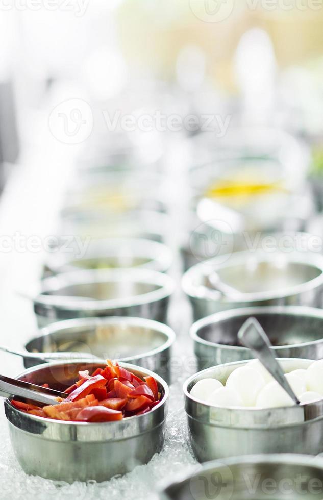 kommen met gemengde verse biologische rode paprika's en groenten in moderne saladebar-display foto