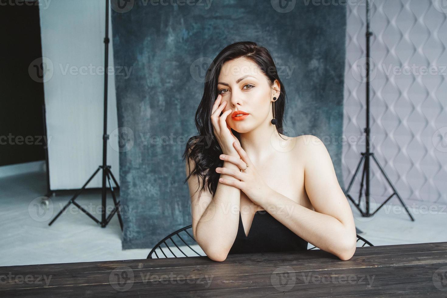 brunette vrouw zittend aan tafel op donkergrijze kopie ruimte achtergrond foto