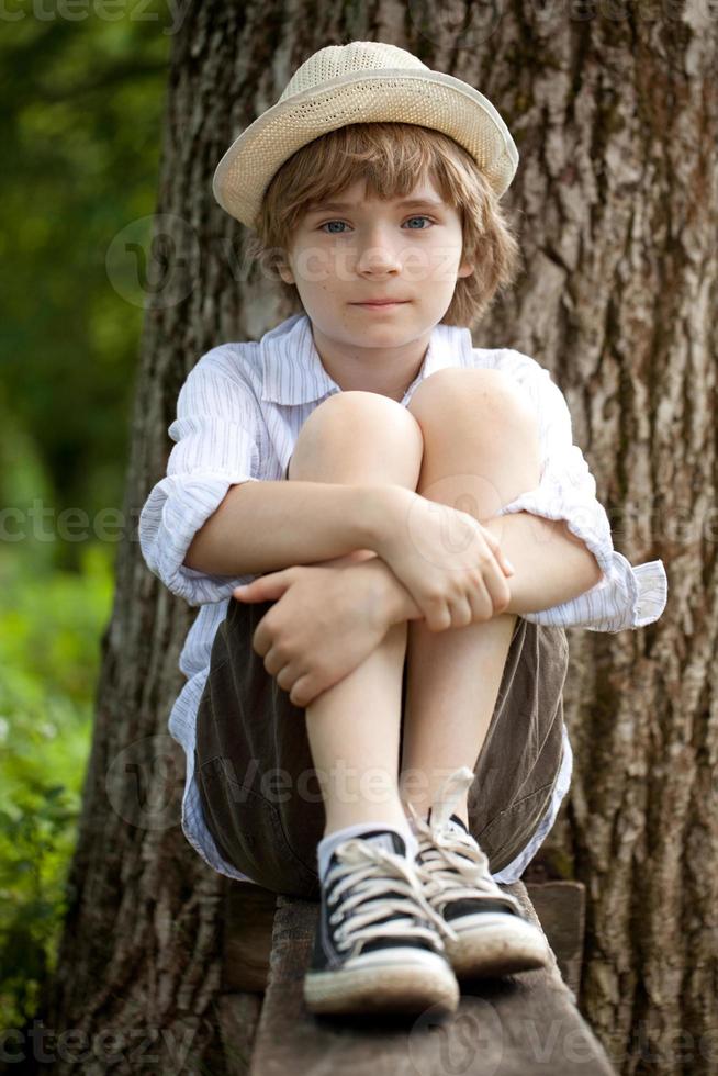 jongen in de hoed op de bank foto