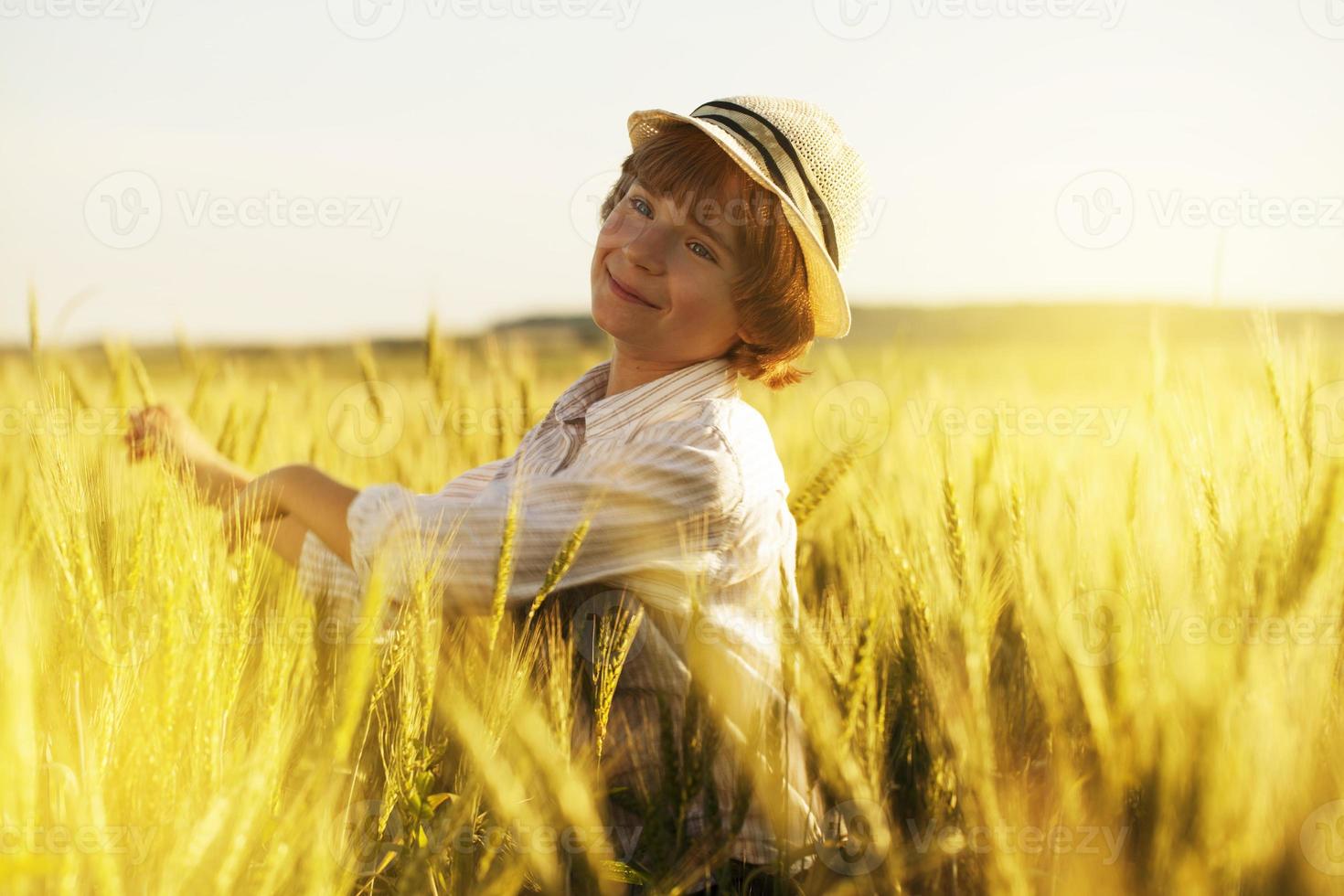 kleine jongen schudt oren van tarwe met zijn handen foto
