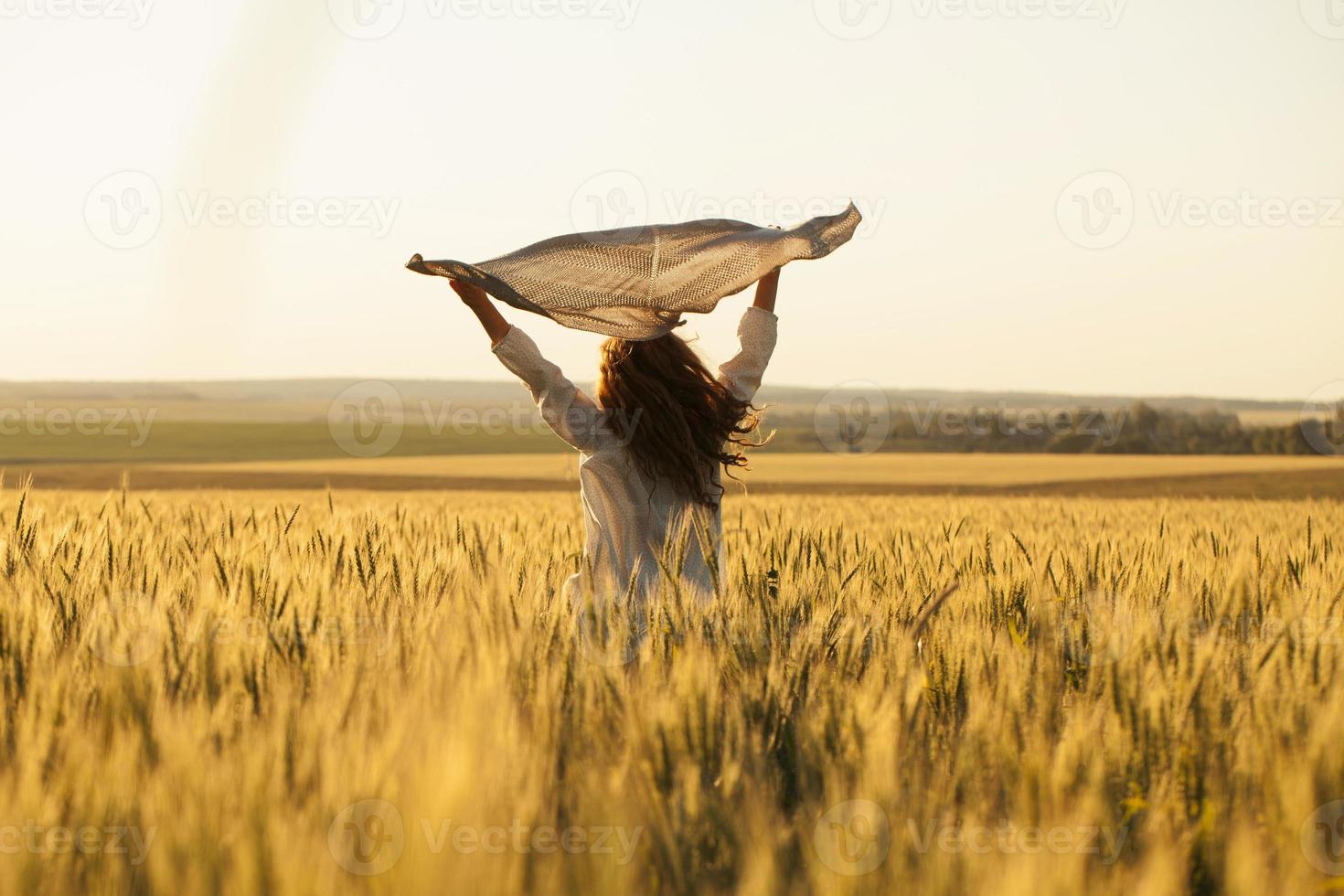 gelukkige vrouw met hoofddoek in het midden van rijp tarweveld foto