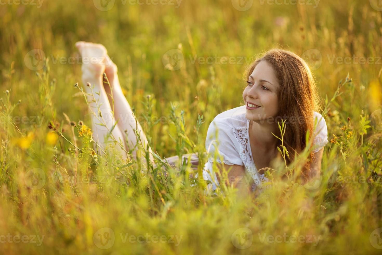 gelukkige vrouw liggend in een veld van gras en bloemen foto