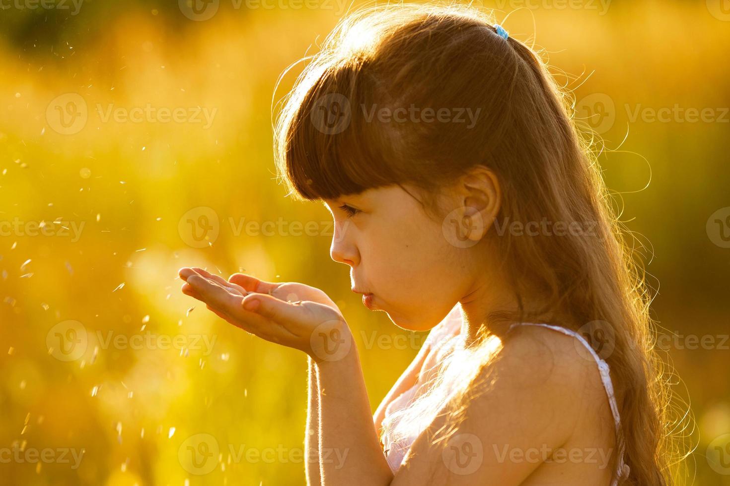 meisje blaast op zaden in de handpalmen foto