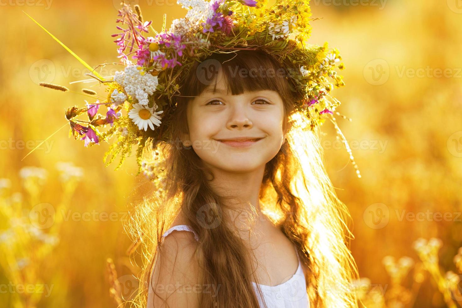 gelukkig schattig meisje met een krans van bloemen foto