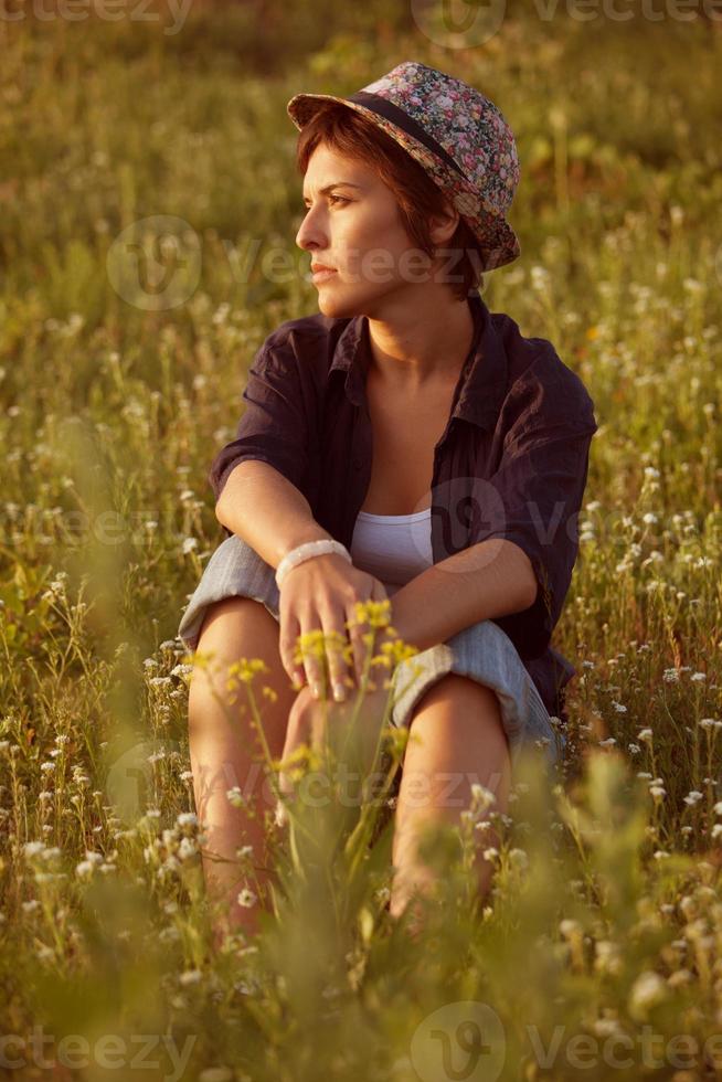 vrouw met hoed zittend tussen wilde bloemen foto