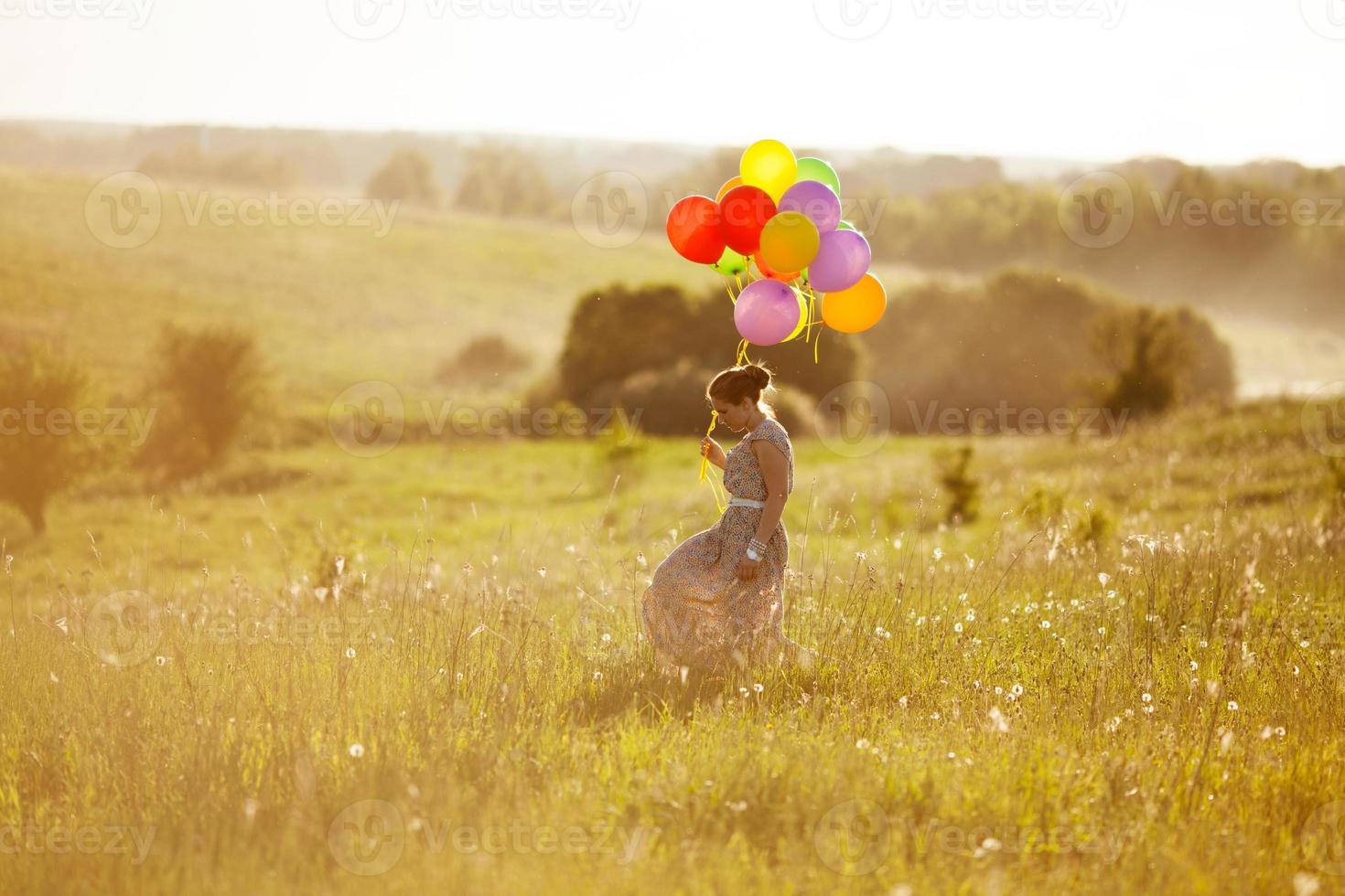 gelukkige jonge vrouw met ballonnen tussen een veld foto