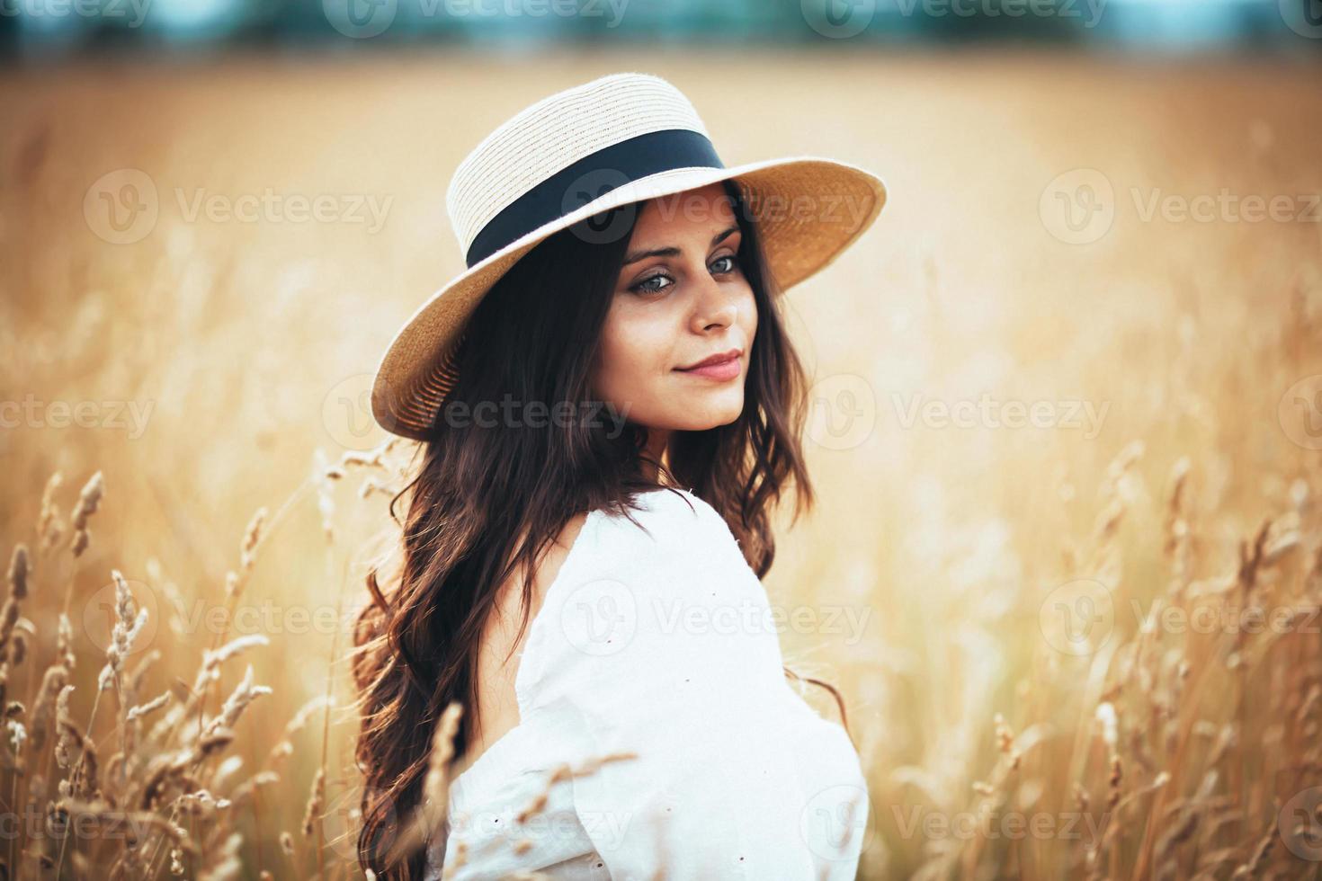 mooie vrouw in strohoed onder veldgras foto