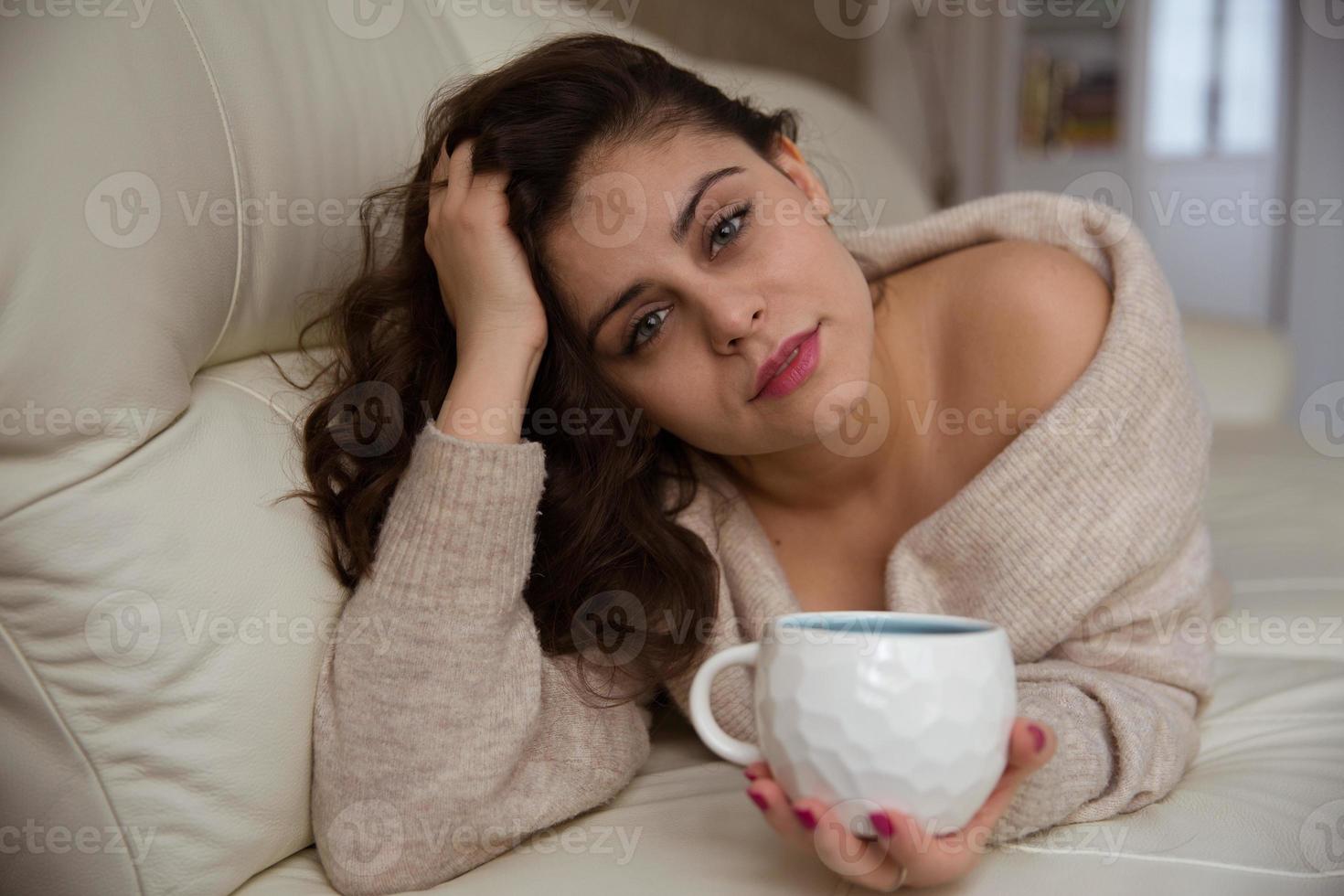 meisje dat op de bank ligt en koffie drinkt foto