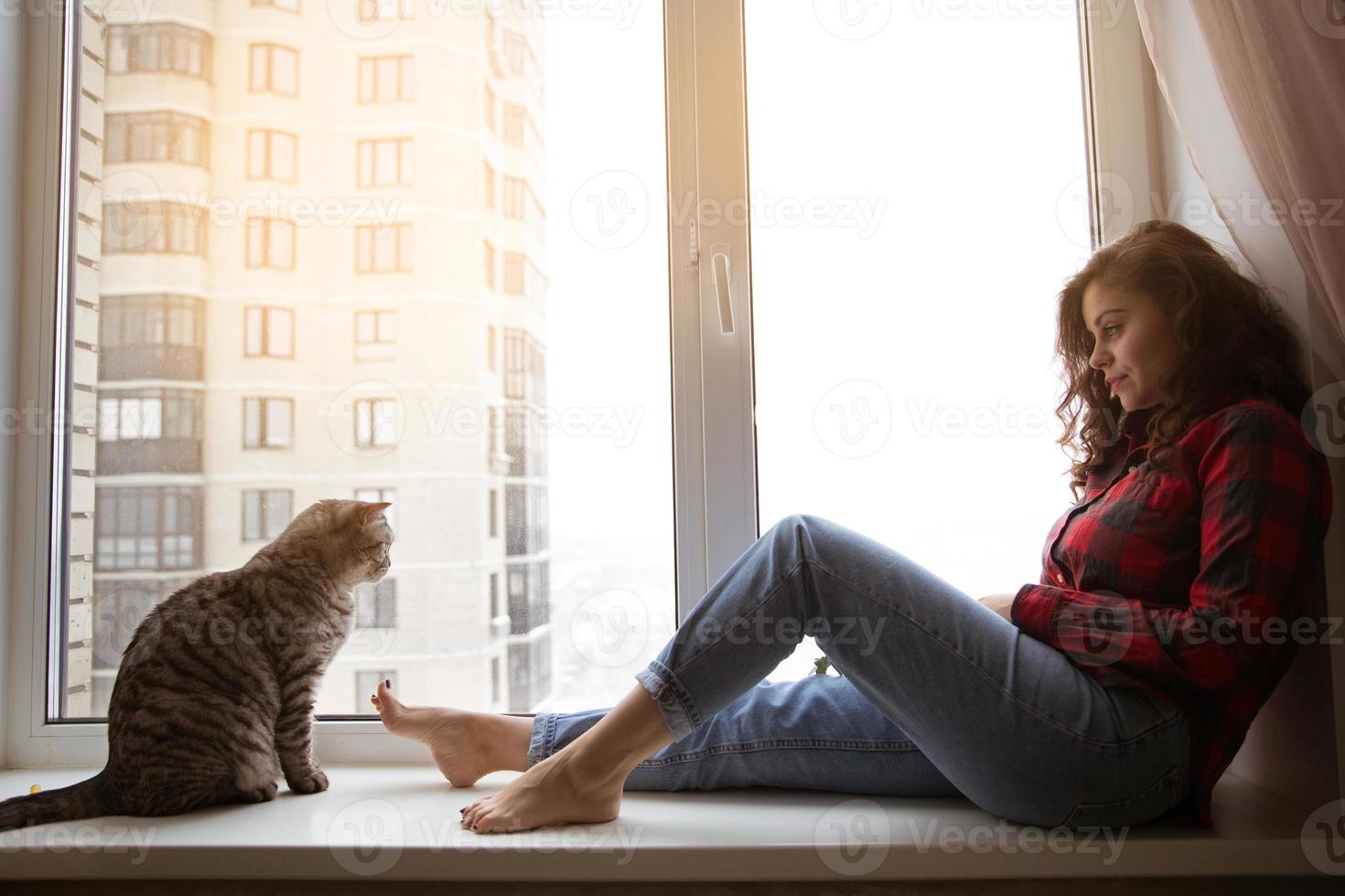 kat en meisje zitten bij het raam foto