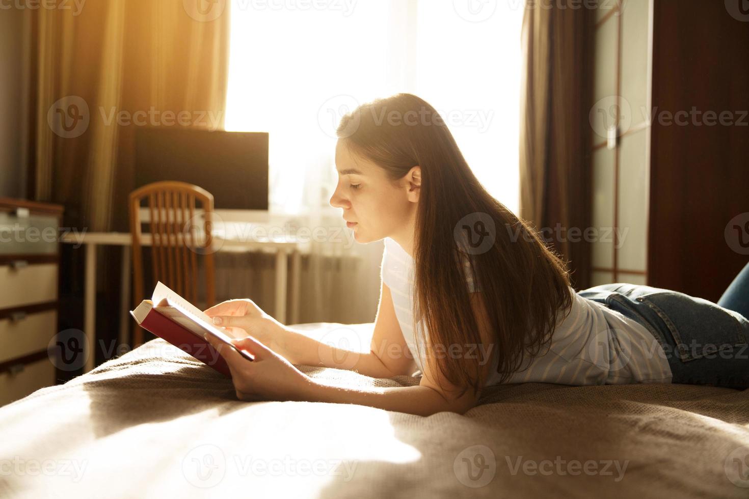 meisje liegt en leest een boek foto