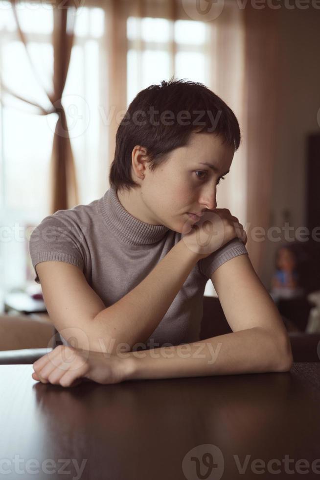 trieste vrouw zitten met gevouwen handen foto