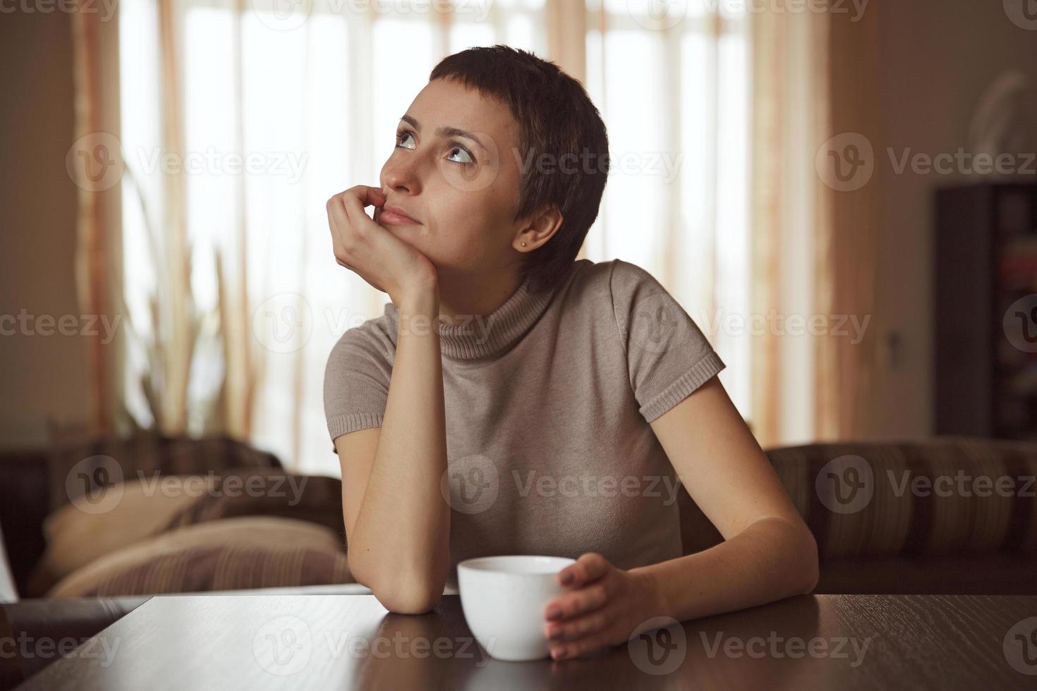 dromerig meisje zit met een kopje koffie foto