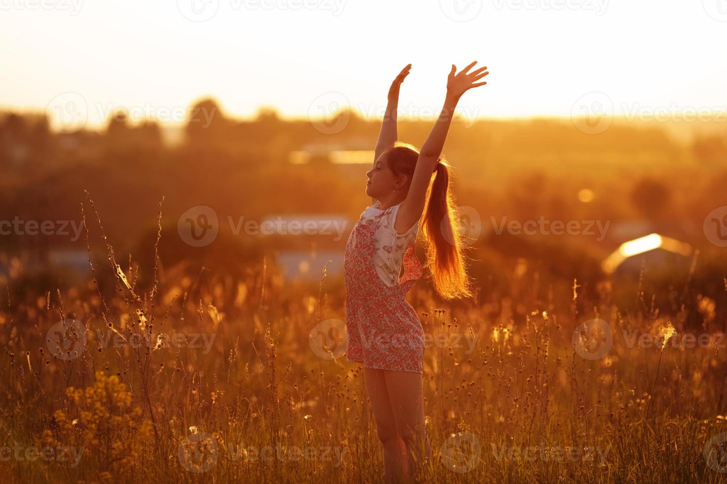 gelukkig meisje in een veld op zomeravond foto