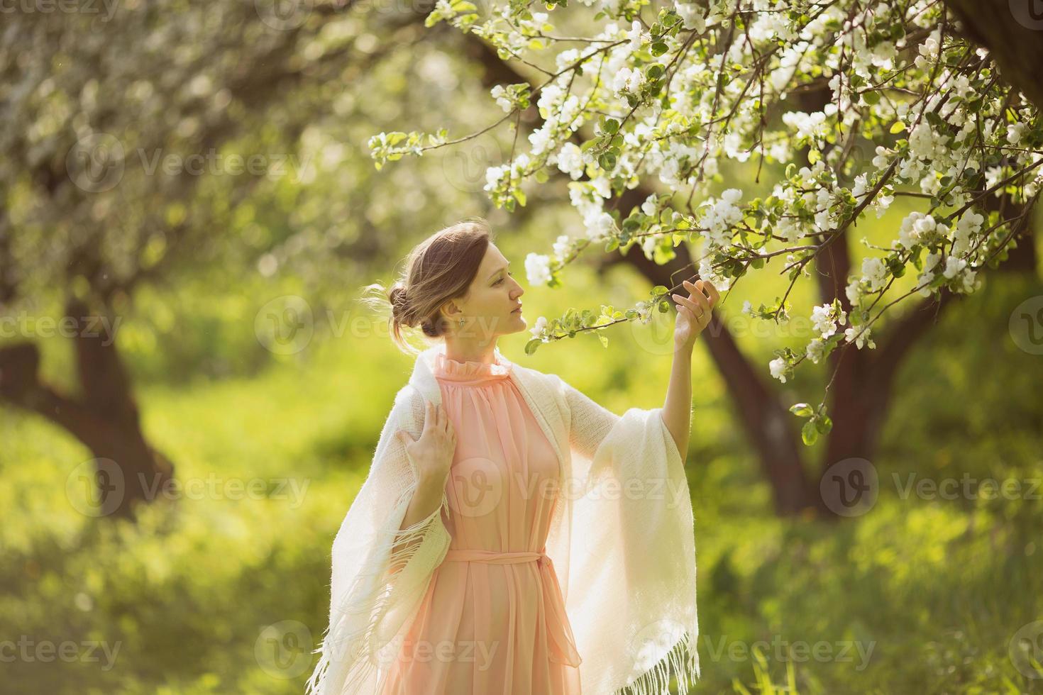 gelukkige vrouw in de buurt van de bloeiende appelboom foto