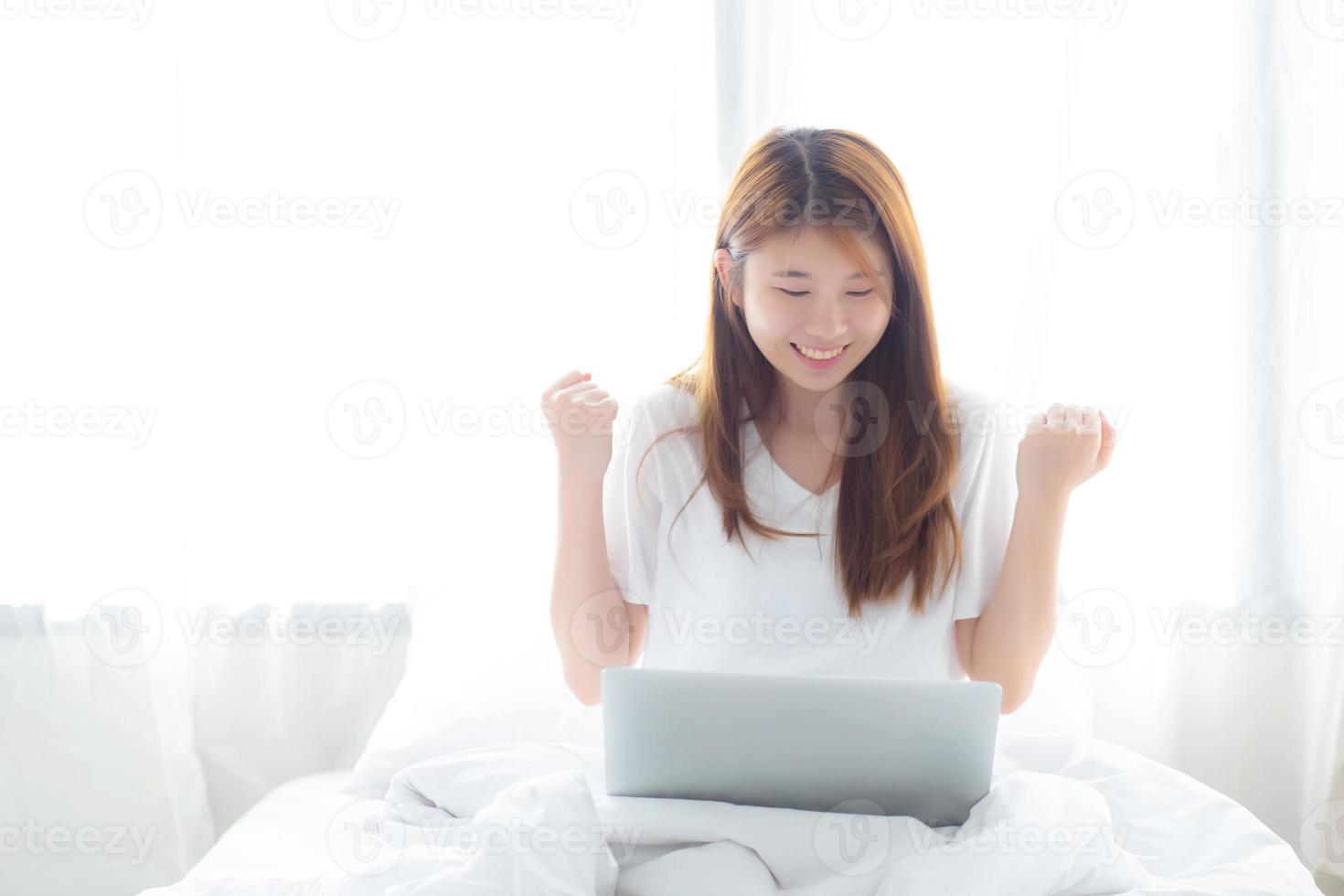 jonge Aziatische vrouw met behulp van laptop werken met succes op bed. foto