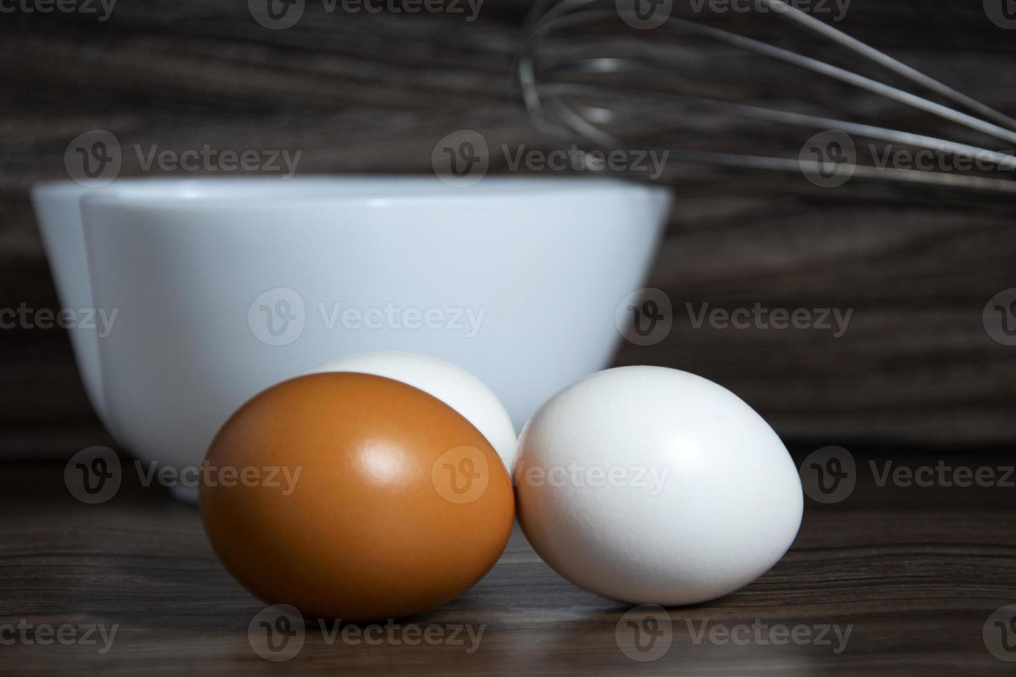 eieren. witte en oranje eieren liggen op de tafel bij de kom. foto
