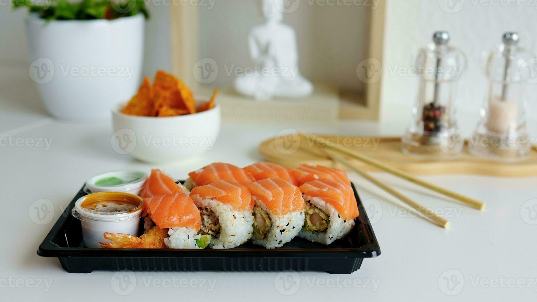sushi rollen met Zalm, gerookt aal, avocado, room kaas Aan een zwart bord Bij huis. sushi menu. levering concept. Japans voedsel. foto