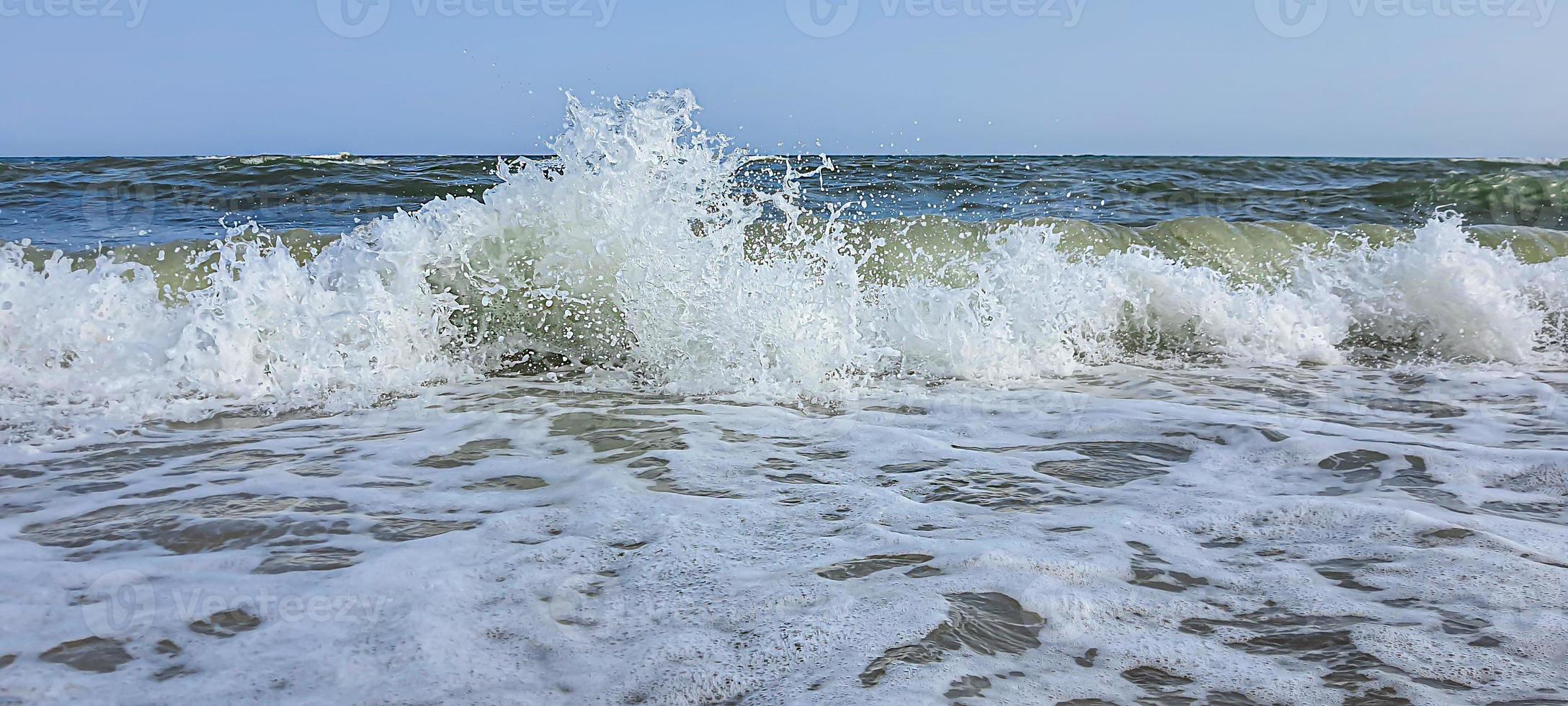 zeegezicht. azuurblauwe kleur van water, golven schuimend op de kust. foto
