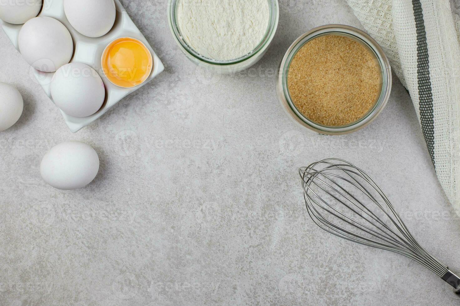 bakken culinaire ingrediënten. eieren, meel, rollend pin, vliegenmepper en keuken textiel Aan helder grijs beton achtergrond. koekjes, taart of taart recept model. top visie. vlak leggen. kopiëren ruimte. foto