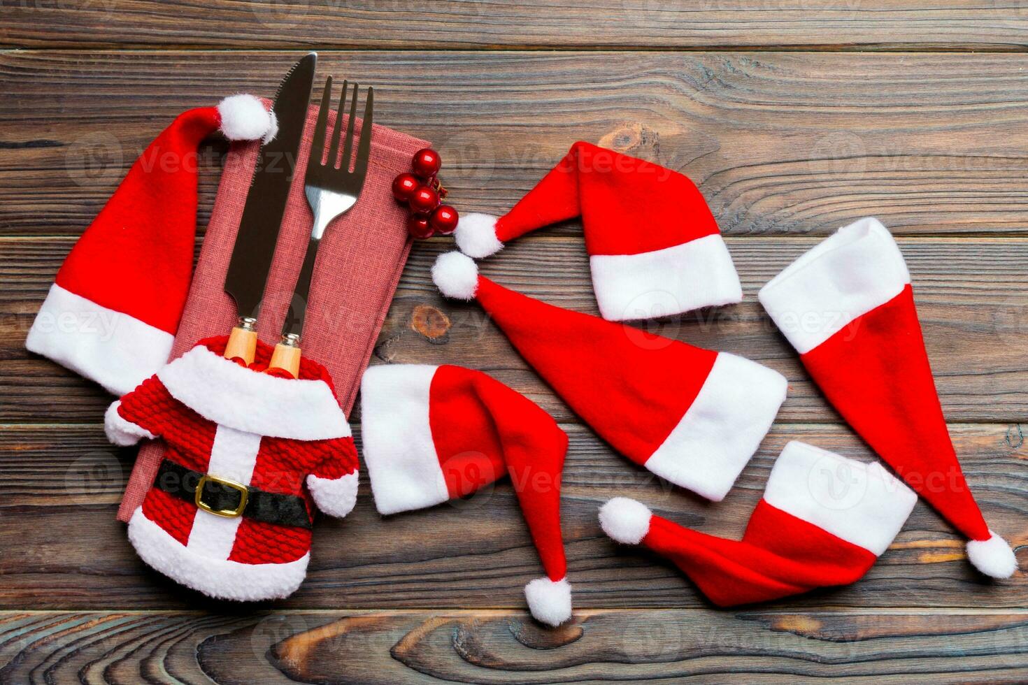 feestelijk reeks van vork en mes Aan houten achtergrond. top visie van nieuw jaar decoraties en de kerstman kleren en hoed. dichtbij omhoog van Kerstmis concept foto