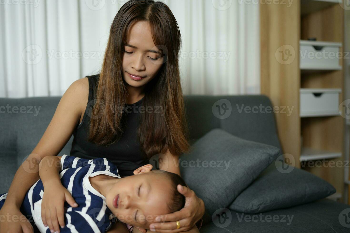 een zoon slaapt Aan zijn moeder ronde binnen de huis. foto
