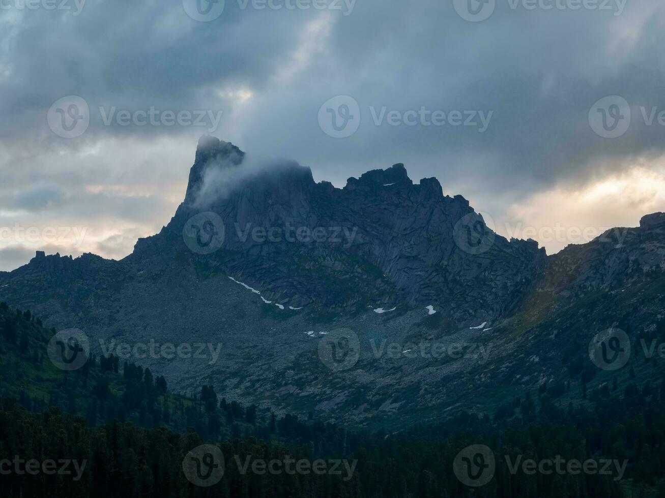 donker sfeervol surrealistische landschap met donker rotsachtig berg top in laag wolken. grijs laag wolk Aan hoog toppunt. hoog zwart rots in laag wolken. surrealistisch somber bergen. west saiyans. foto