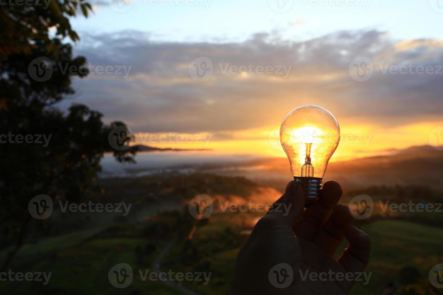 hand met een gloeilamp bij zonsondergang foto