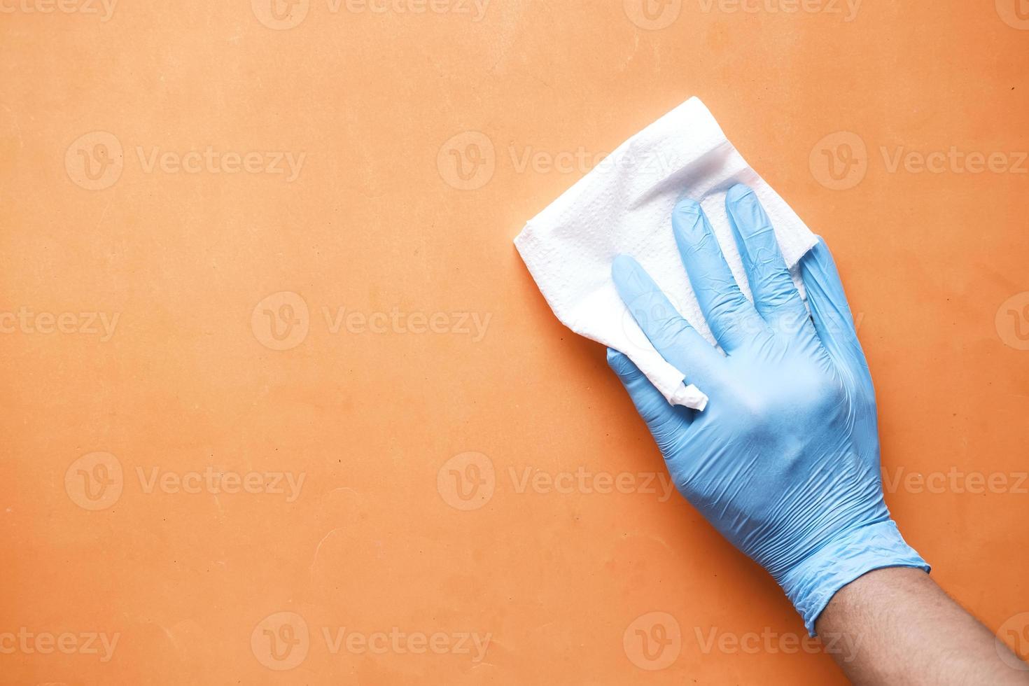 hand in blauwe rubberen handschoenen schoonmaaktafel met doek foto