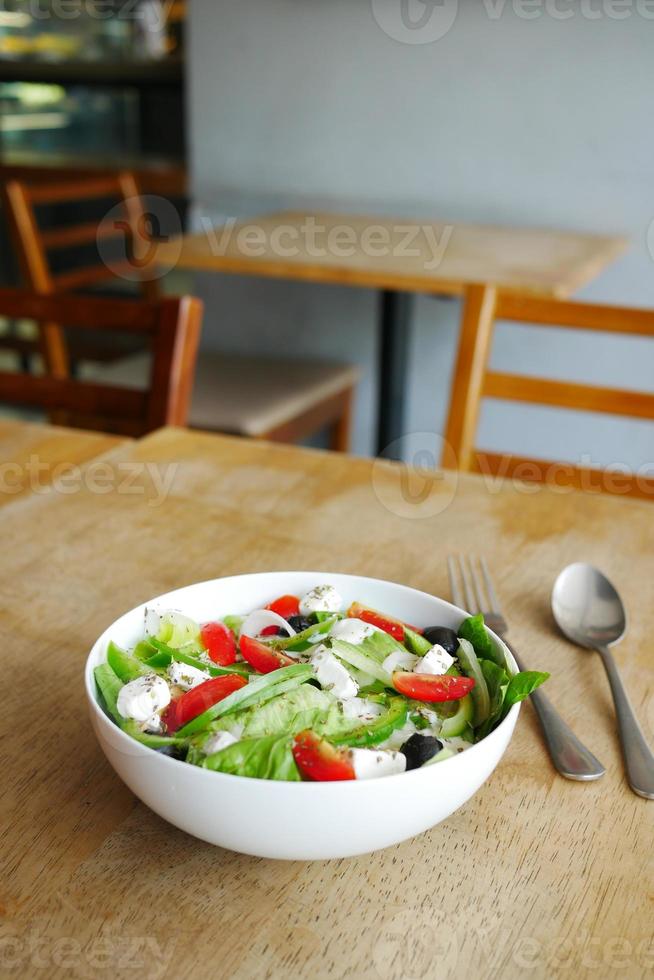 Griekse salade in een kom op cafétafel met kopieerruimte foto