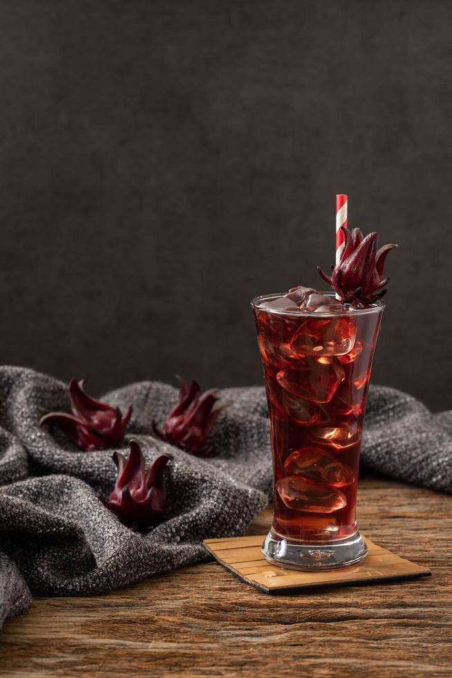 roselle helder glas met vers roselle fruit op houten tafel foto