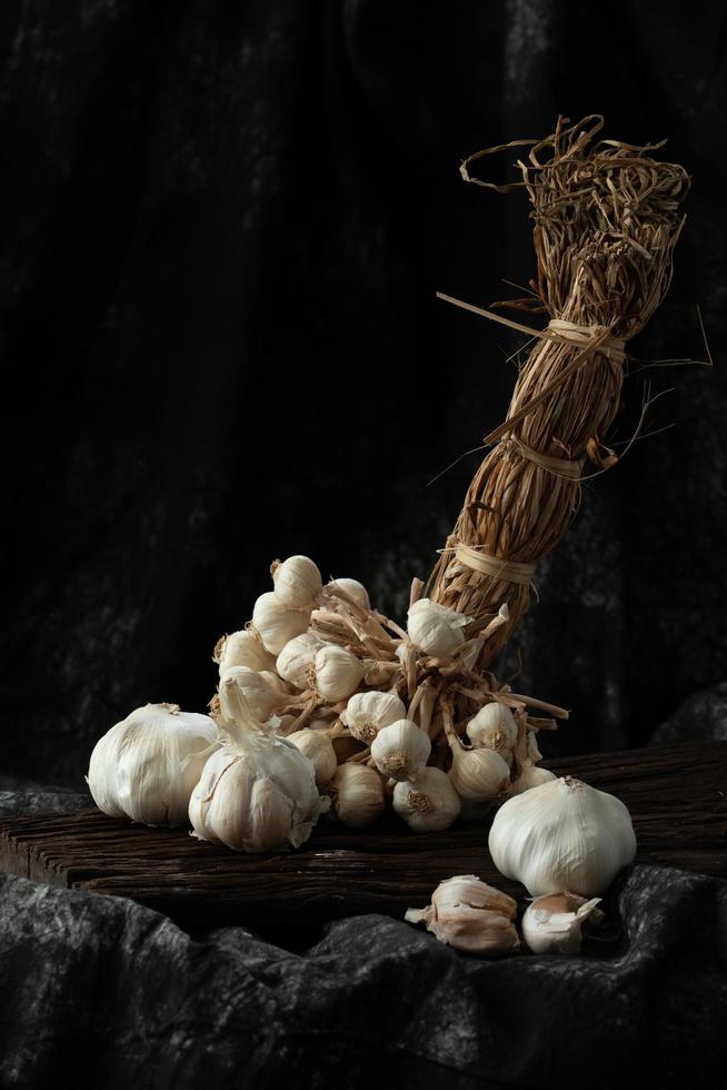 knoflookteentjes en bol op vintage houten zwarte doek foto