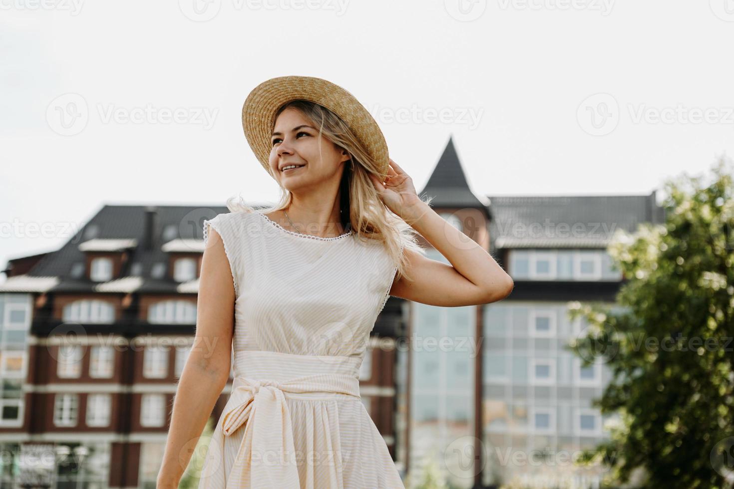 een mooie blondine loopt door een stad. vrouw in witte jurk foto