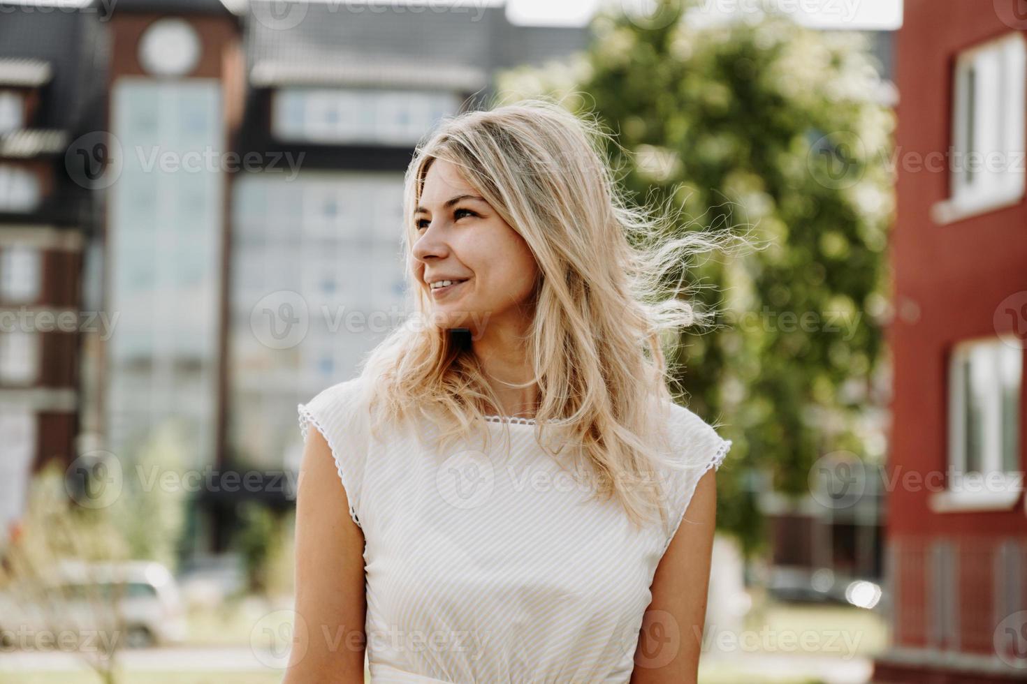 een jonge blonde in een witte jurk op de achtergrond van een Europese stad foto